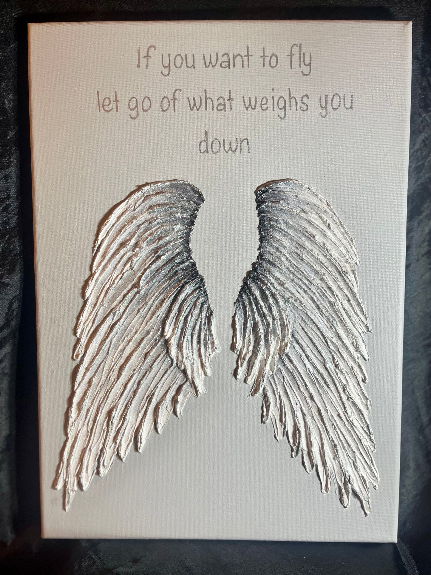 Canvas with silver grey angel wings and motivational quote on a light grey background