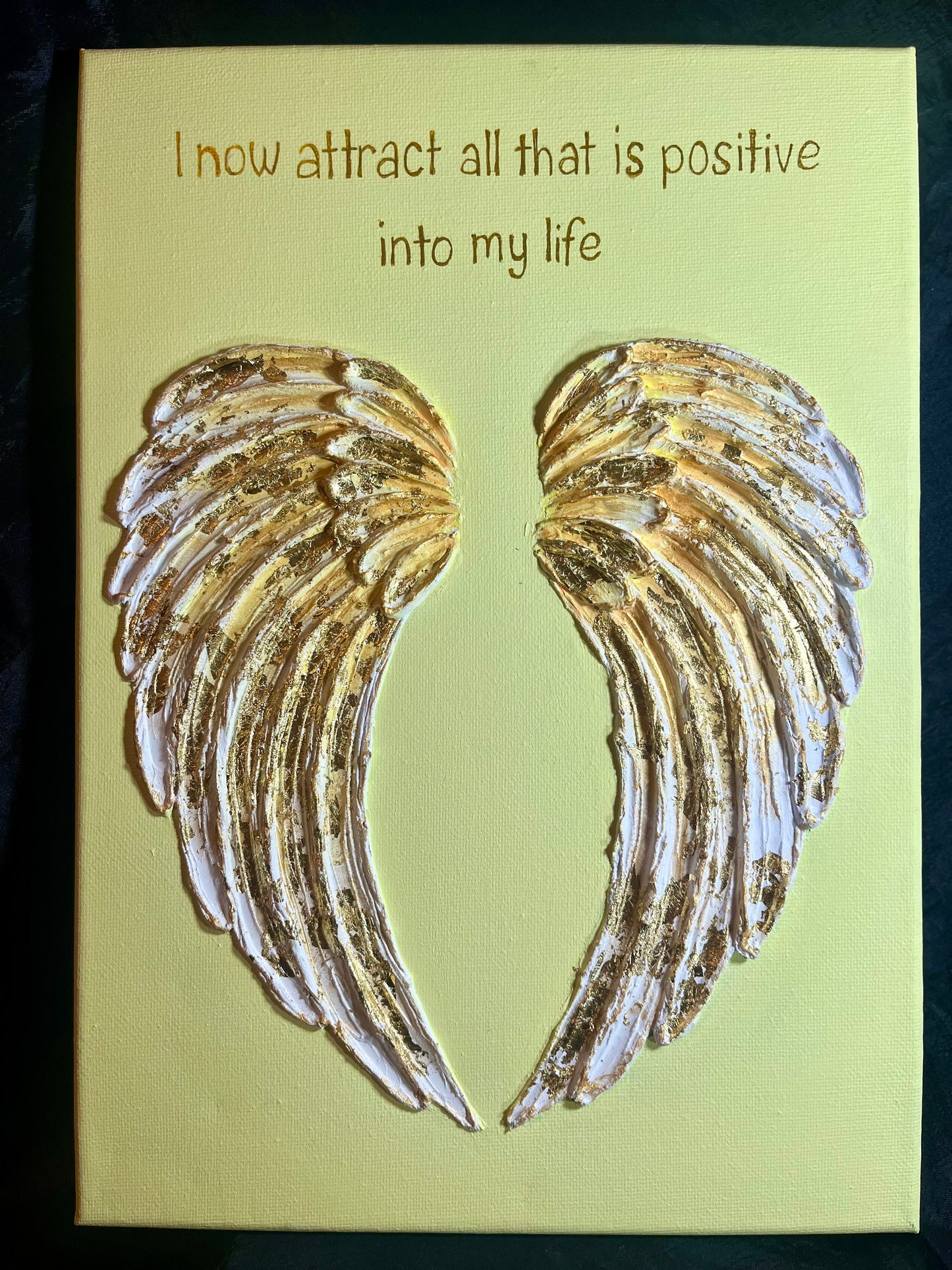 Canvas with golden angel wings and inspirational quote on a yellow background