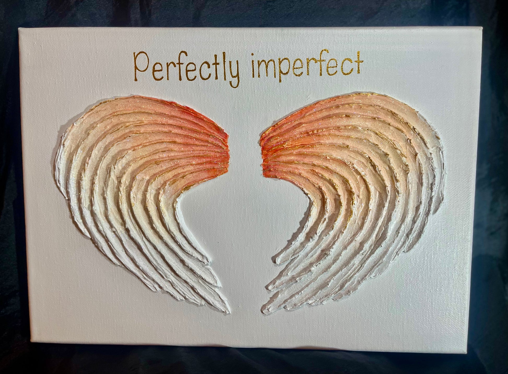Canvas with angel wings and 'Perfectly imperfect' gold text on a white background
