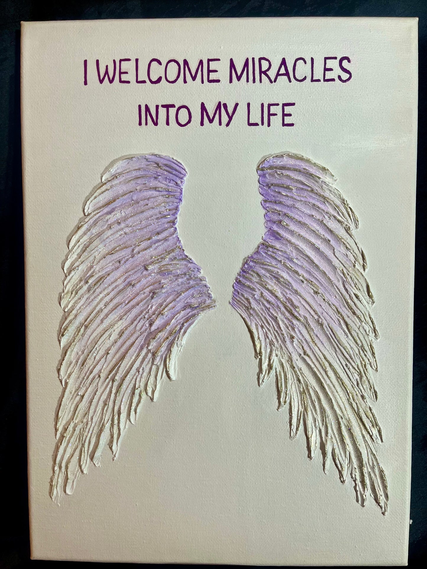 Canvas with lilac angel wings and text 'I welcome miracles into my life' on a white background