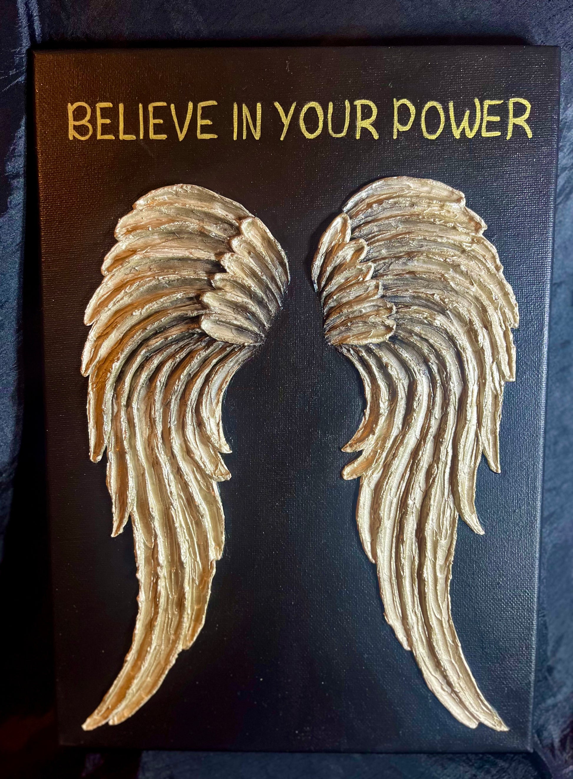 Canvas with gold textured angel wings and 'BELIEVE IN YOUR POWER' text on a dark background