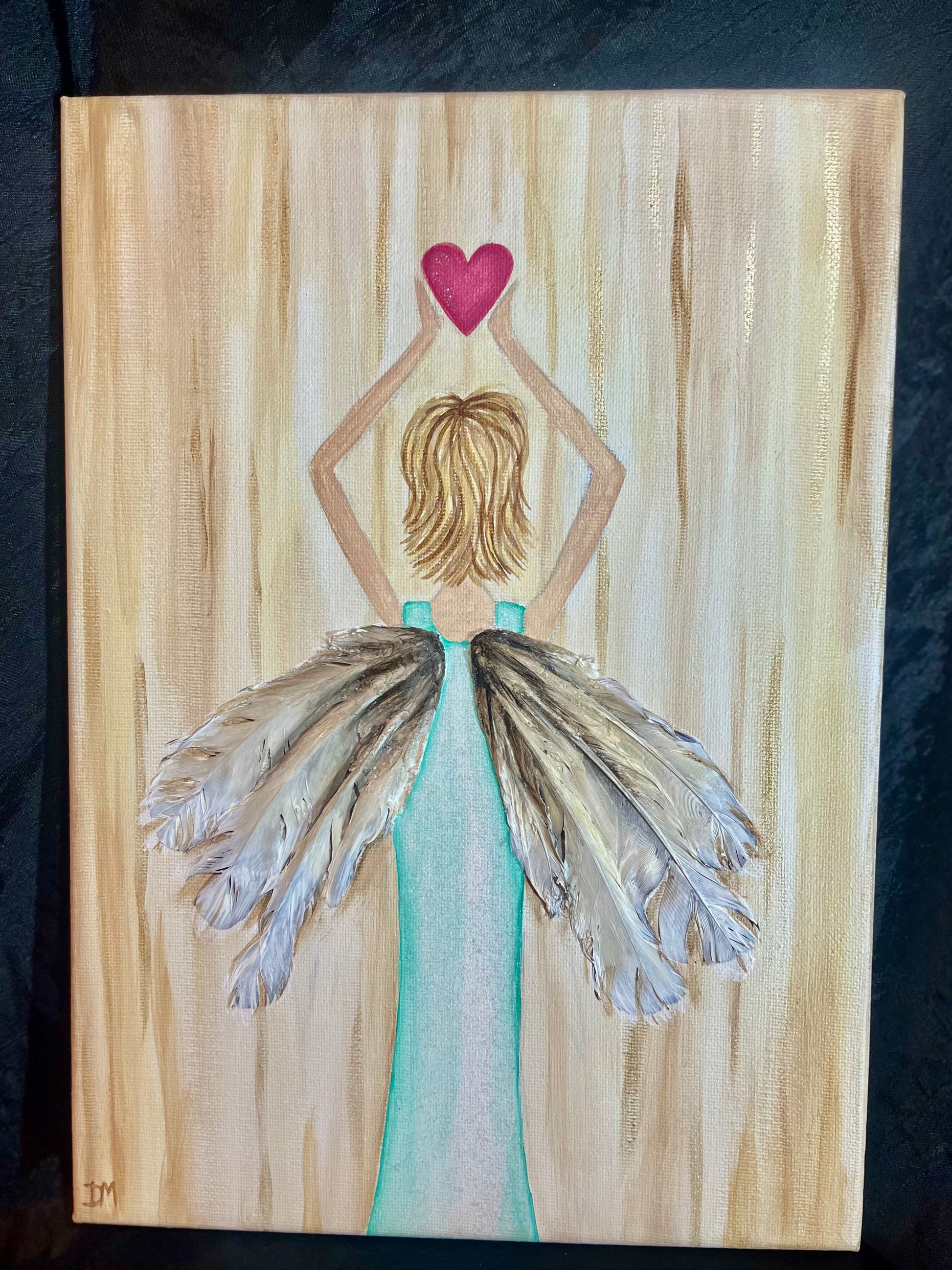 Painting of an angel in a blue dress with feathered wings holding a pink heart on a canvas with real feather detail